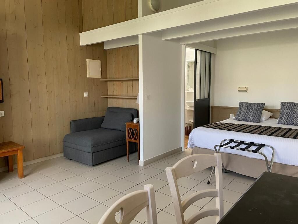 A room with a bed, a sofa, a small table, and a chair.
