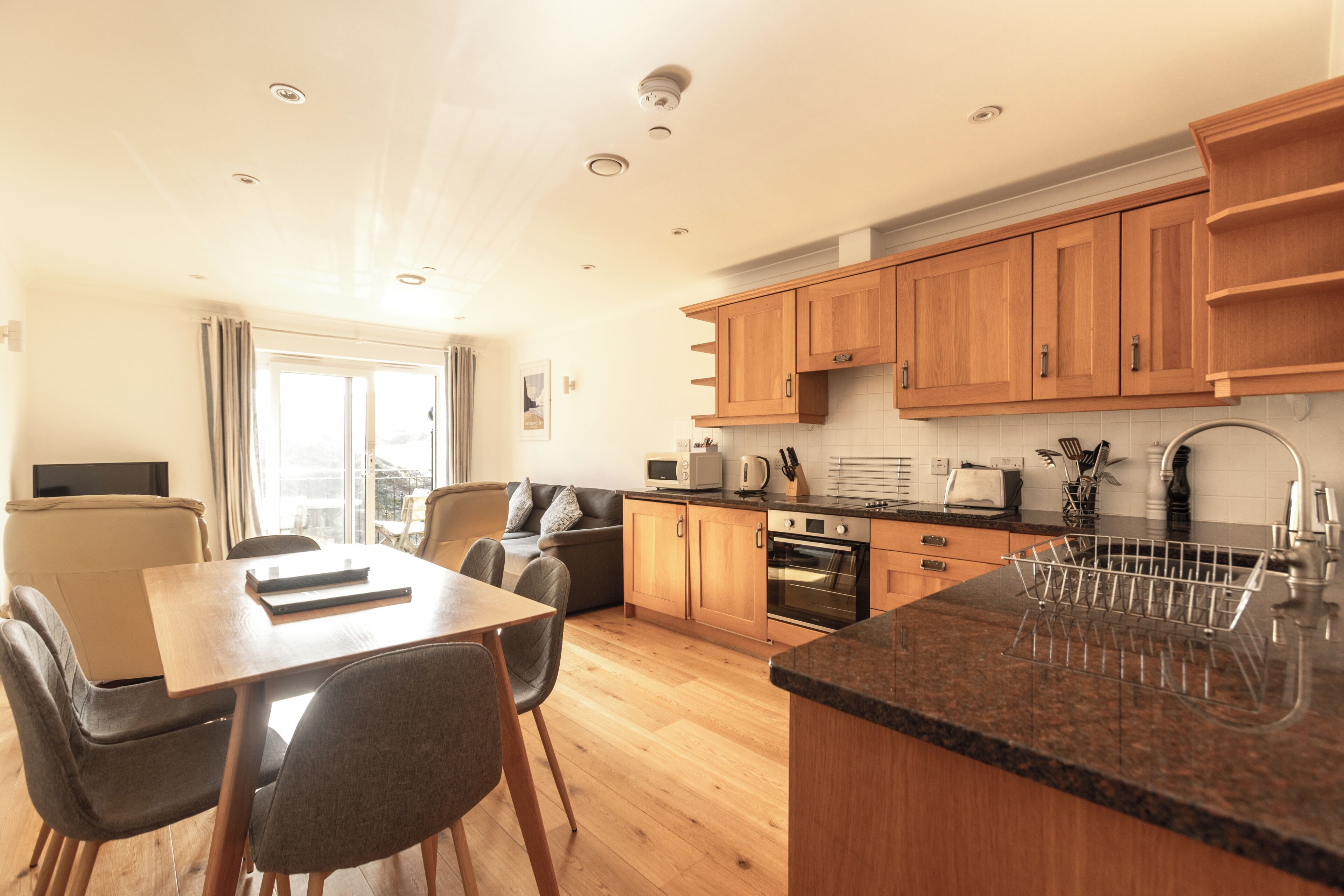 A modern kitchen with wooden cabinets, a granite countertop, and a built-in oven.
