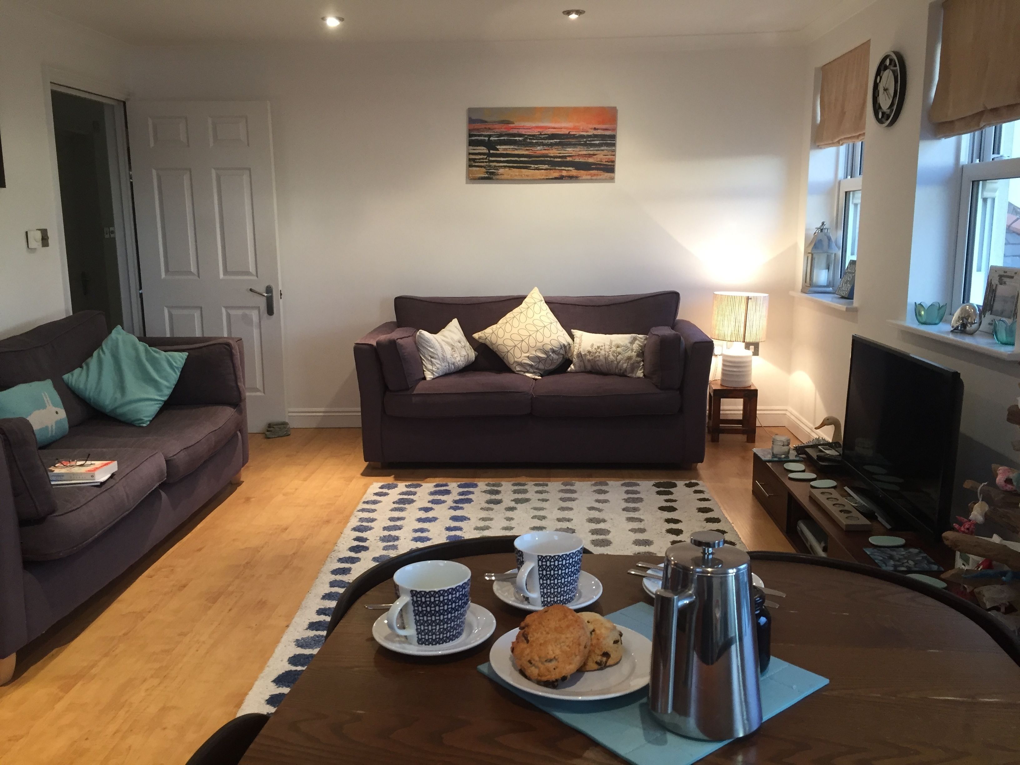 A living room with a sofa, coffee table, and a painting on the wall.