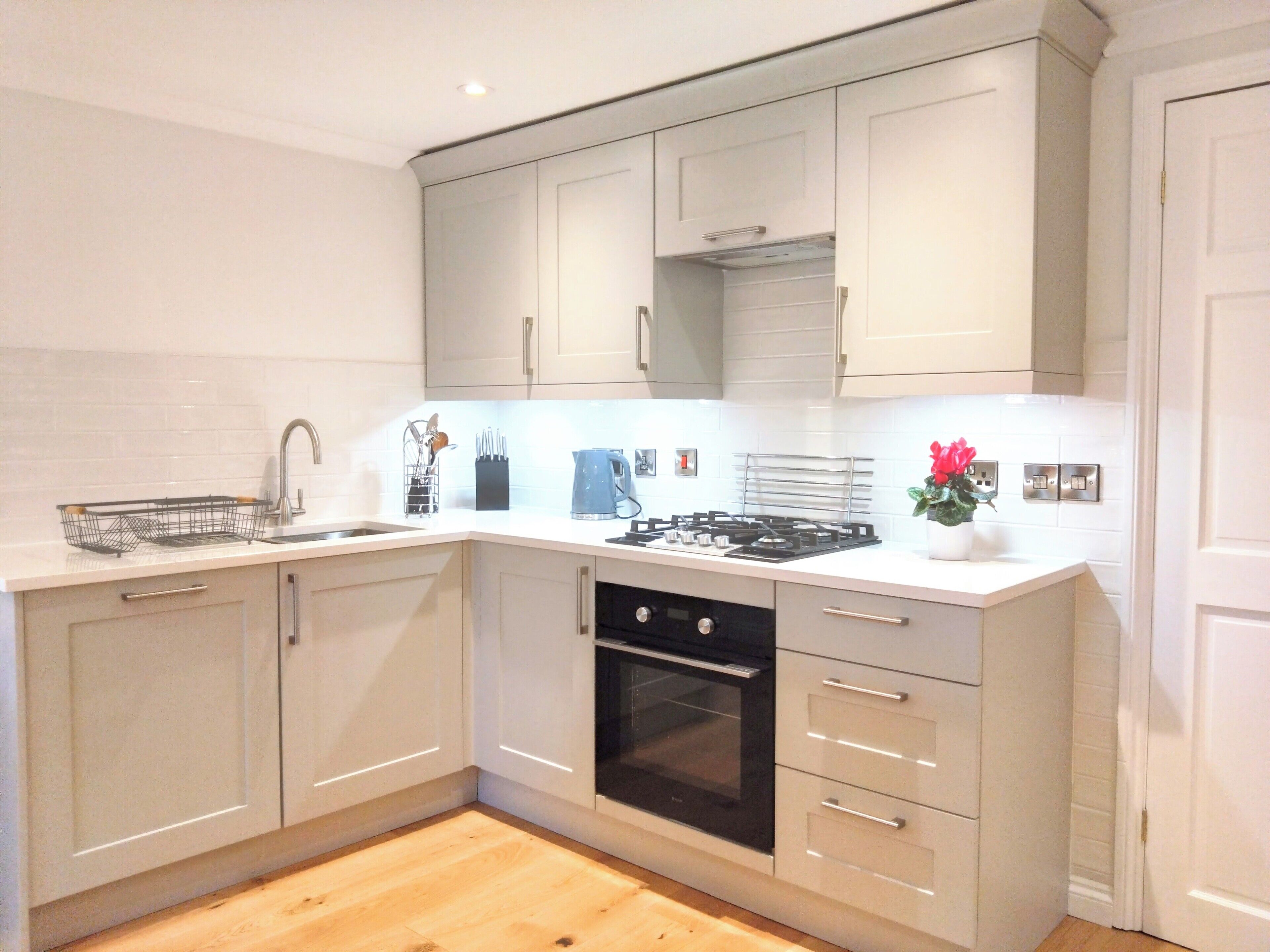 A modern kitchen with white cabinetry, a stainless steel sink, and a gas stove.