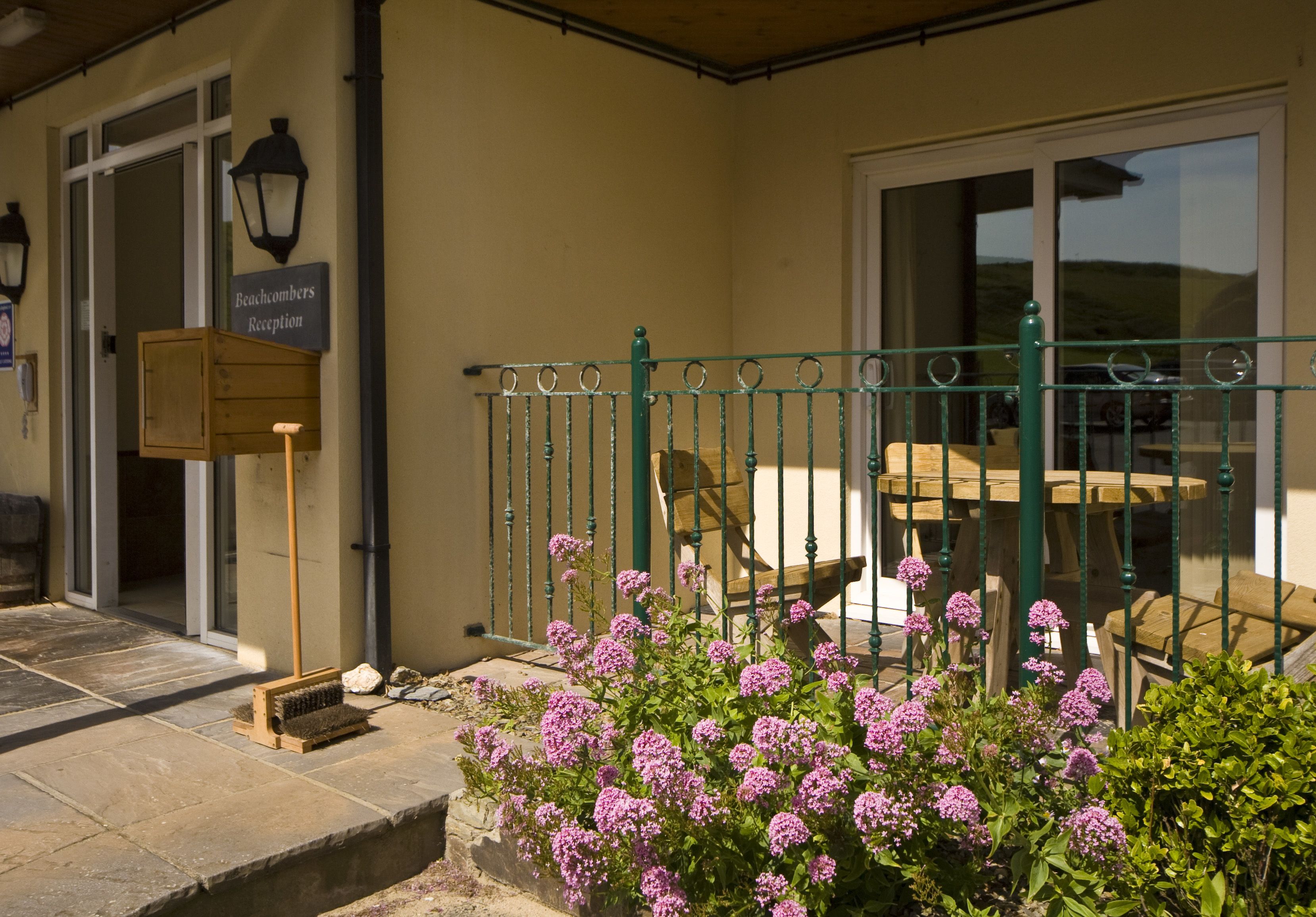 A reception area with a wooden bench, a metal fence, and a sign reading "Beachcombers Reception."