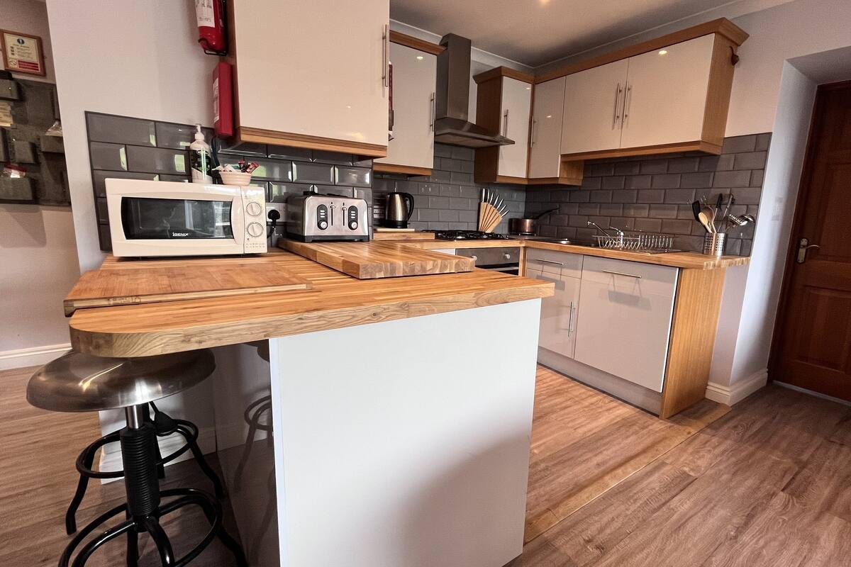 Una cocina moderna con encimera de madera, armarios blancos y estufa integrada.