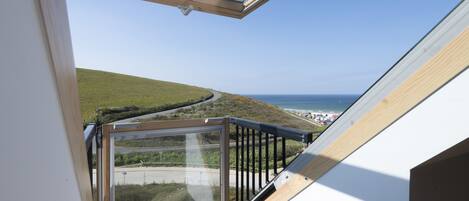A balcony with a clear view of a coastal landscape, including a road and beach.