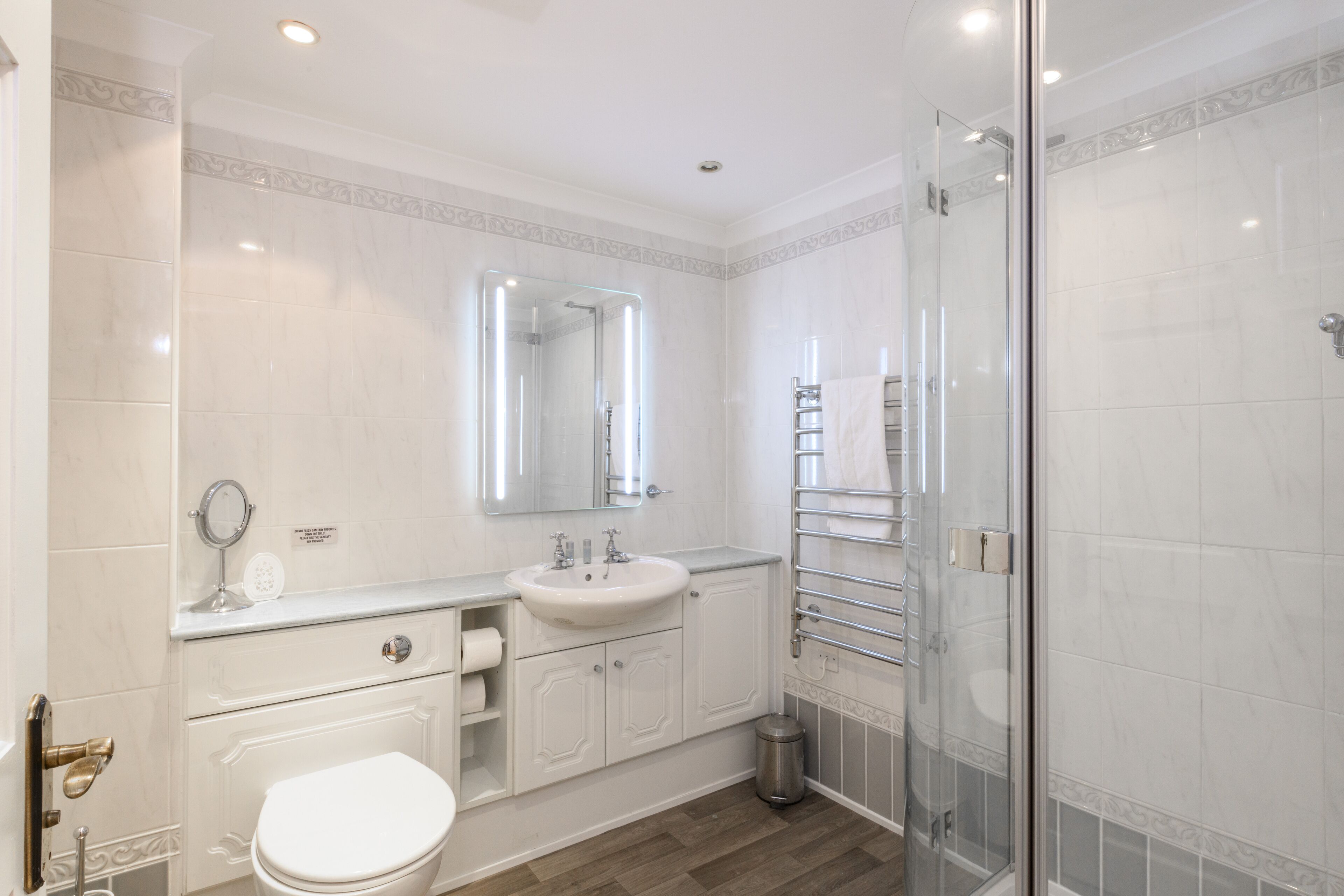 A modern bathroom with a white sink, mirror, and toilet.