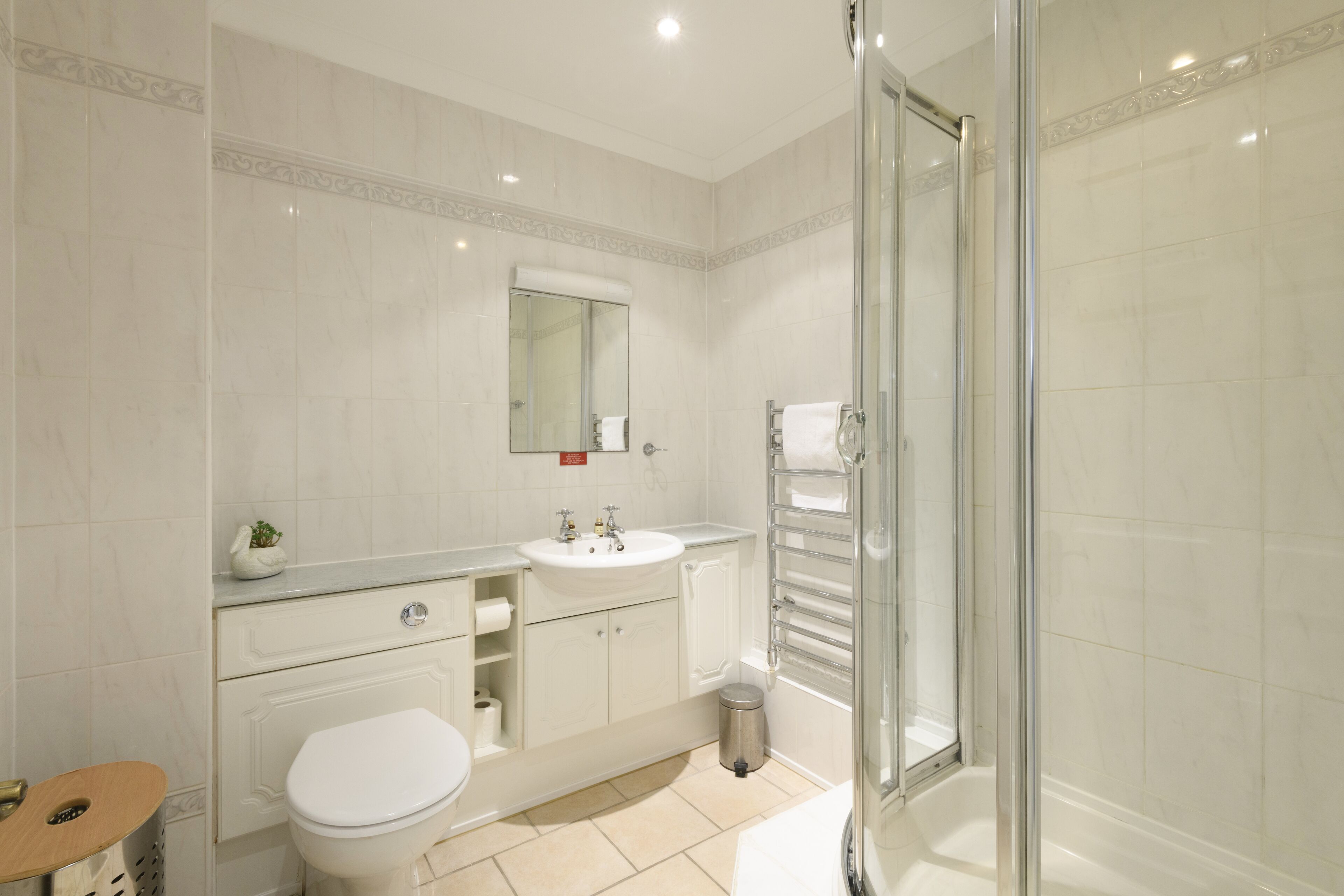 Une salle de bain moderne équipée de toilettes, d’un lavabo et d’une douche à parois de verre.