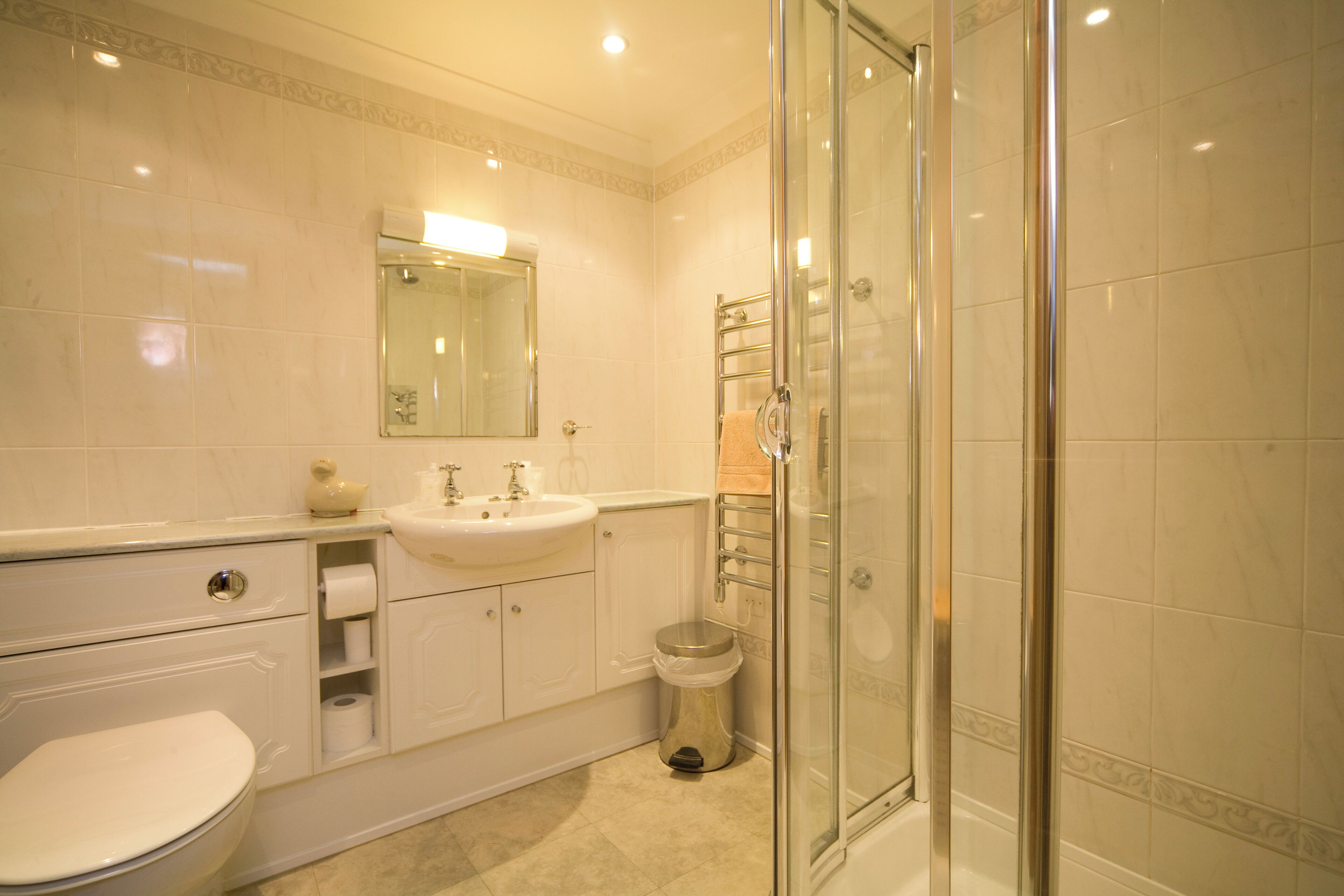 Un baño moderno con cabina de ducha acristalada, un lavamanos blanco y un inodoro.