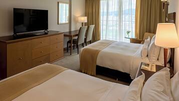 Una camera d'albergo con due letti, televisione, una scrivania e una sedia.