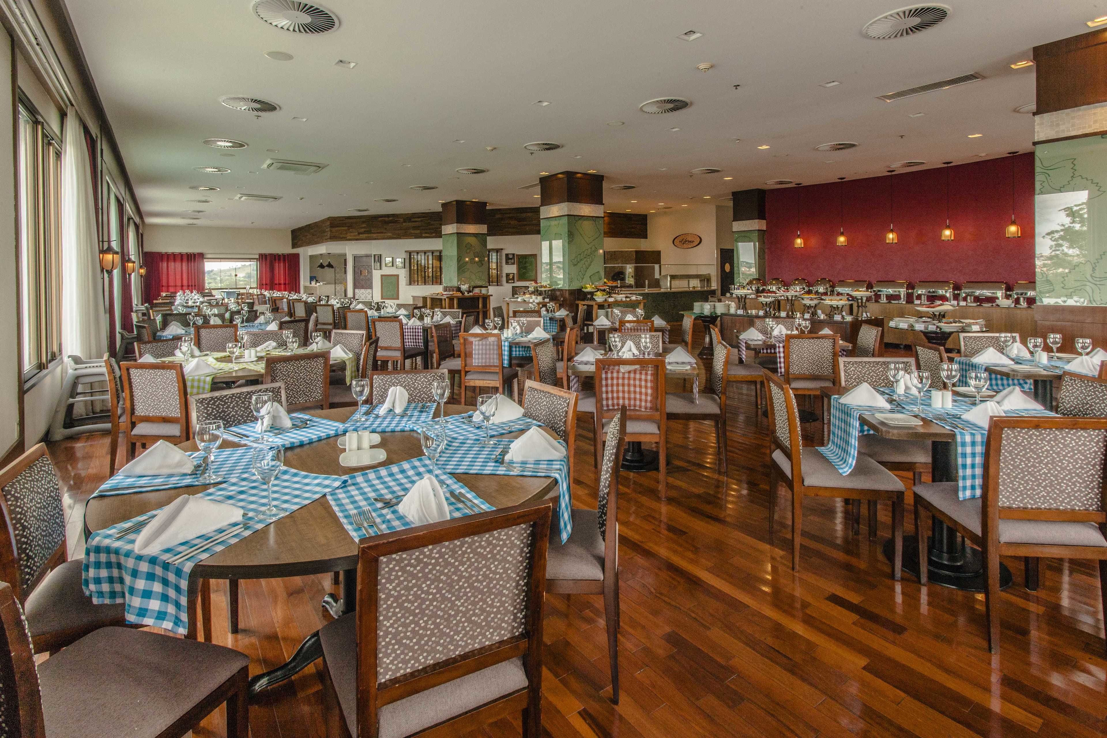 A spacious dining area with multiple tables set for dining, featuring checkered tablecloths and wooden chairs.