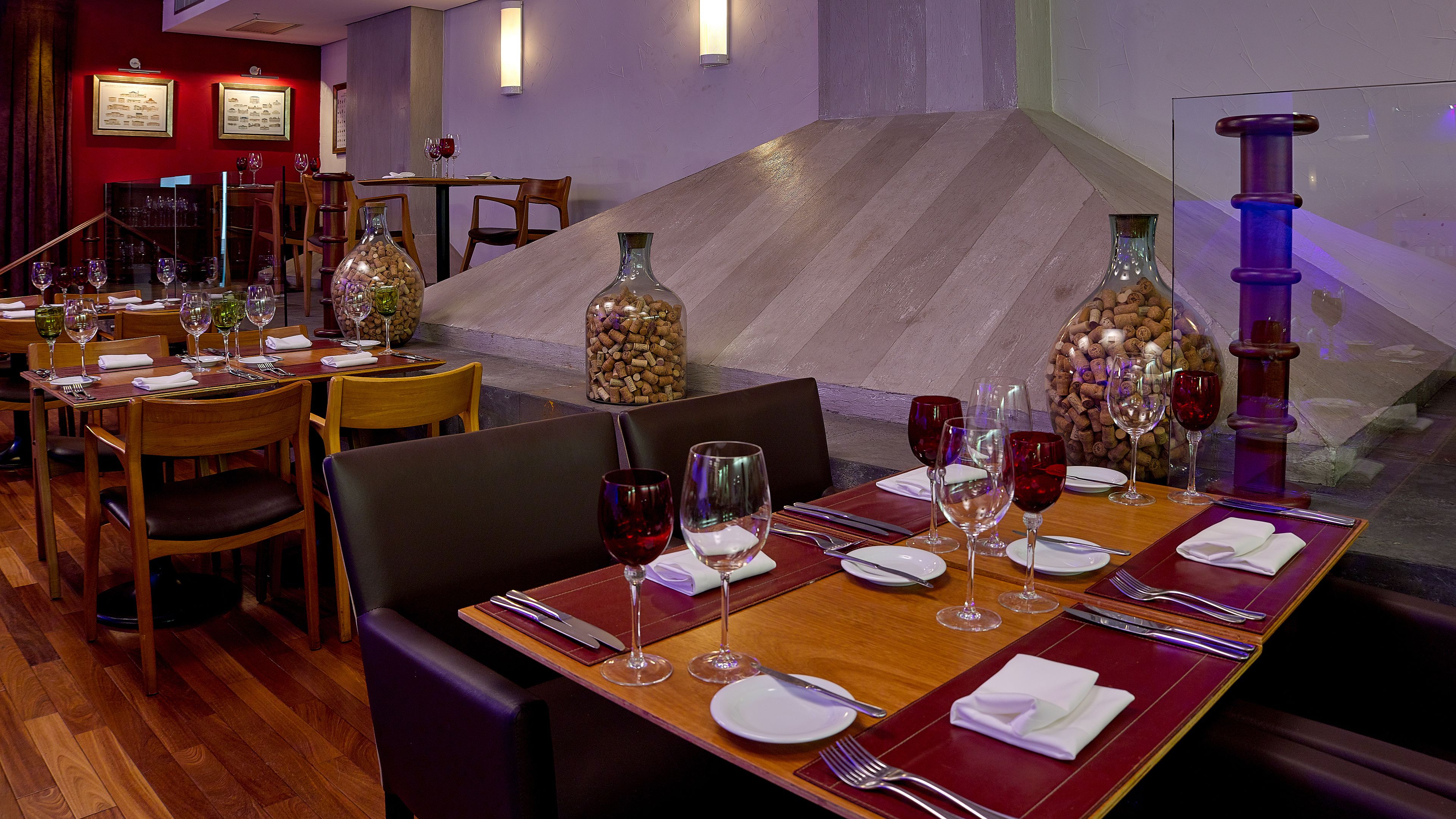 A restaurant interior with wooden tables, chairs, and wine glasses.