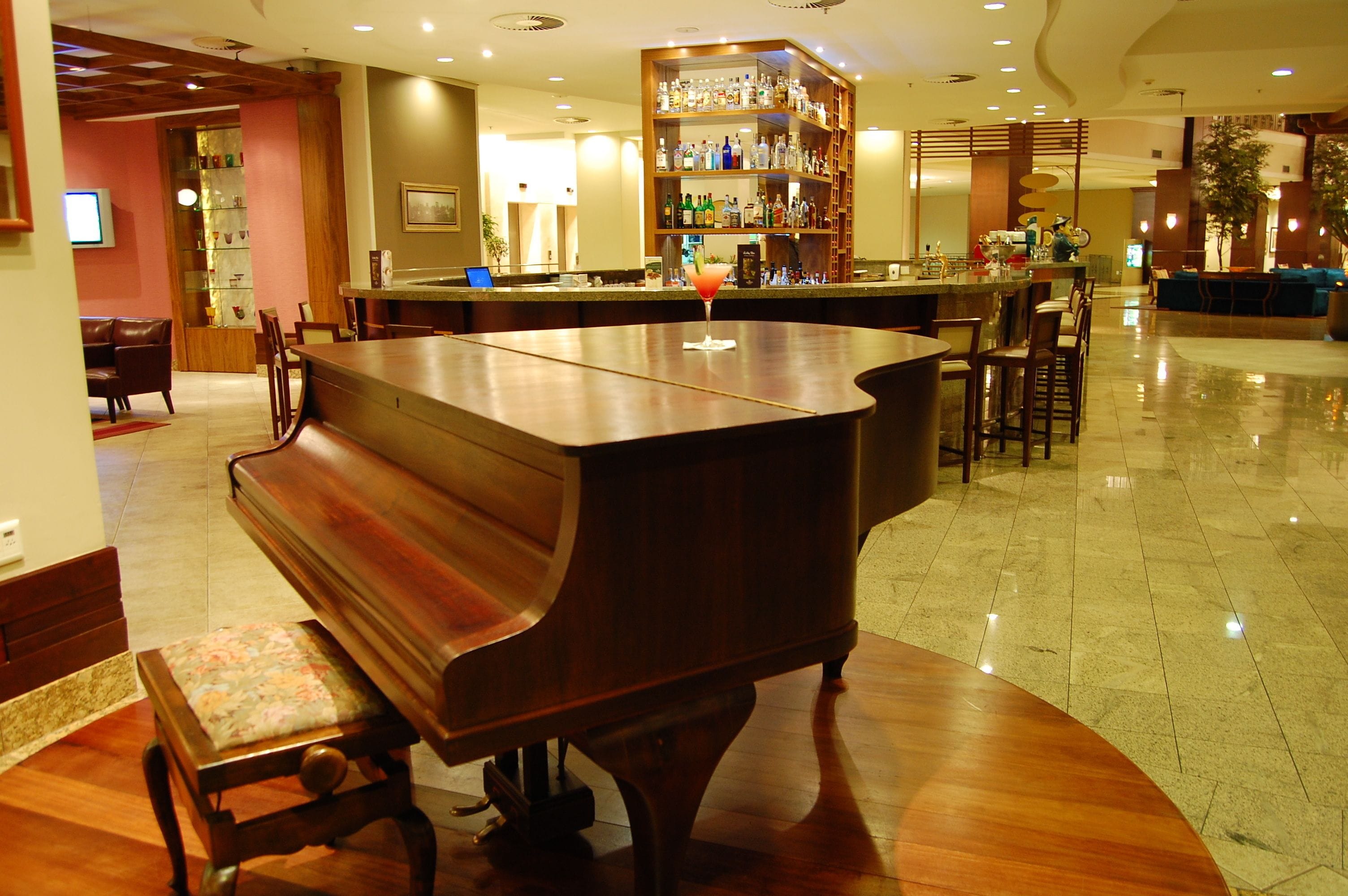 A bar area with a piano, seating, and a well-stocked liquor shelf.
