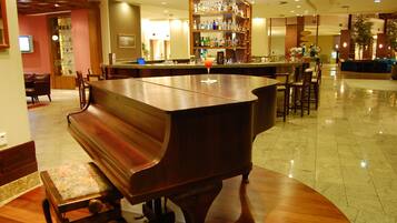 A bar area with a piano, seating, and a well-stocked liquor shelf.