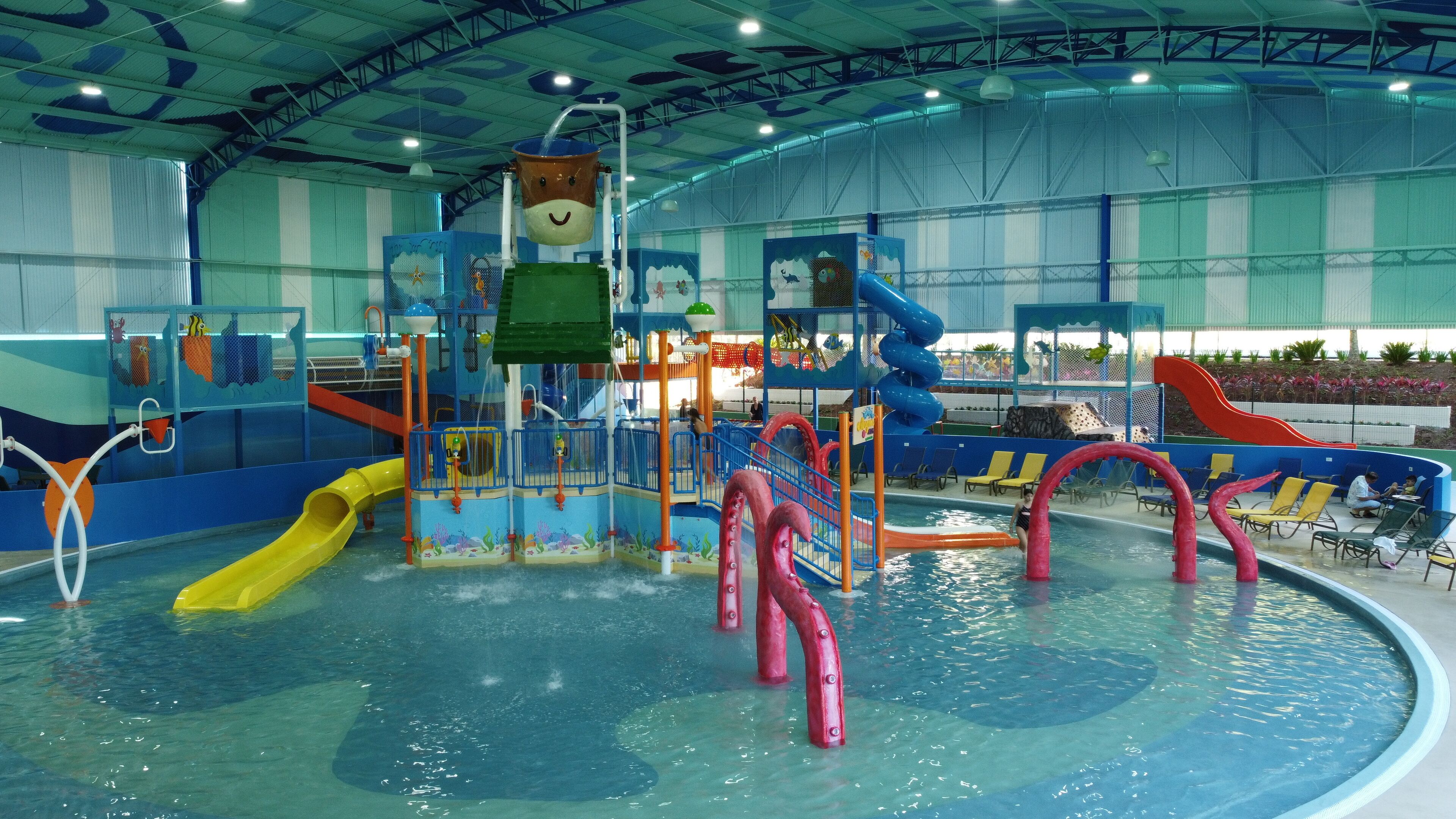 Parque aquático interno com toboáguas, piscina e estruturas de recreação.