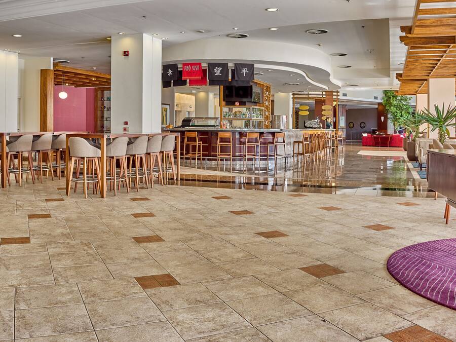 A modern lobby with a bar area, seating arrangements, and a piano.