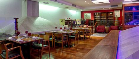 Un restaurant avec des tables et des chaises en bois, un meuble à vin et un fauteuil rouge.