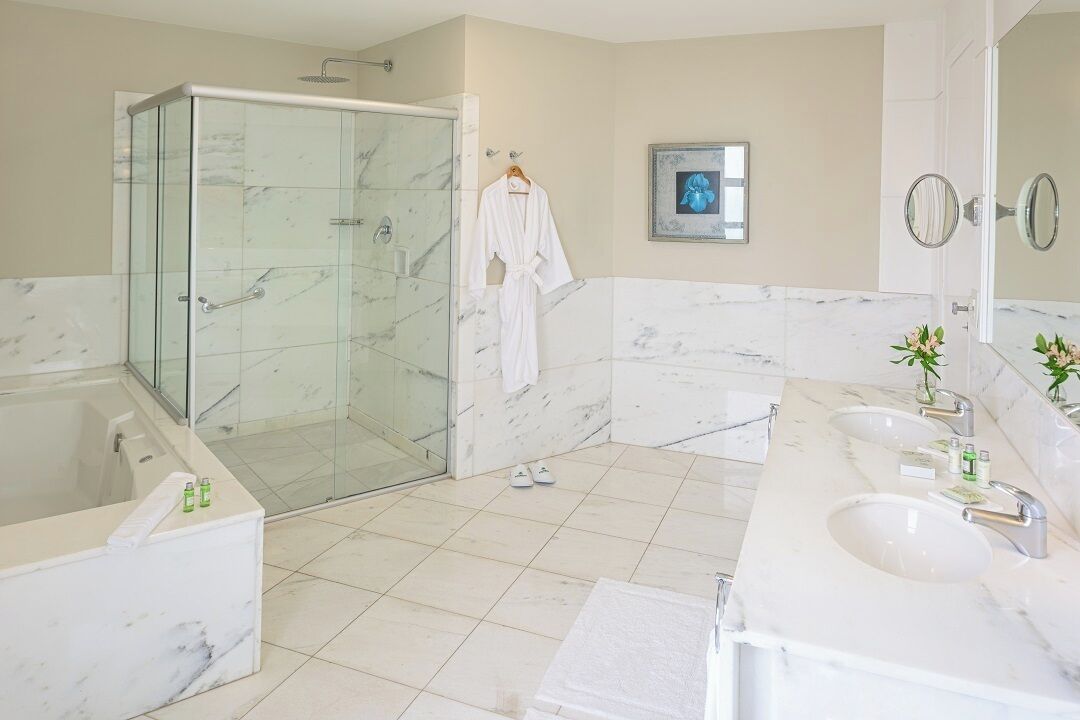 A modern bathroom with a glass-enclosed shower, a marble vanity, and a large mirror.