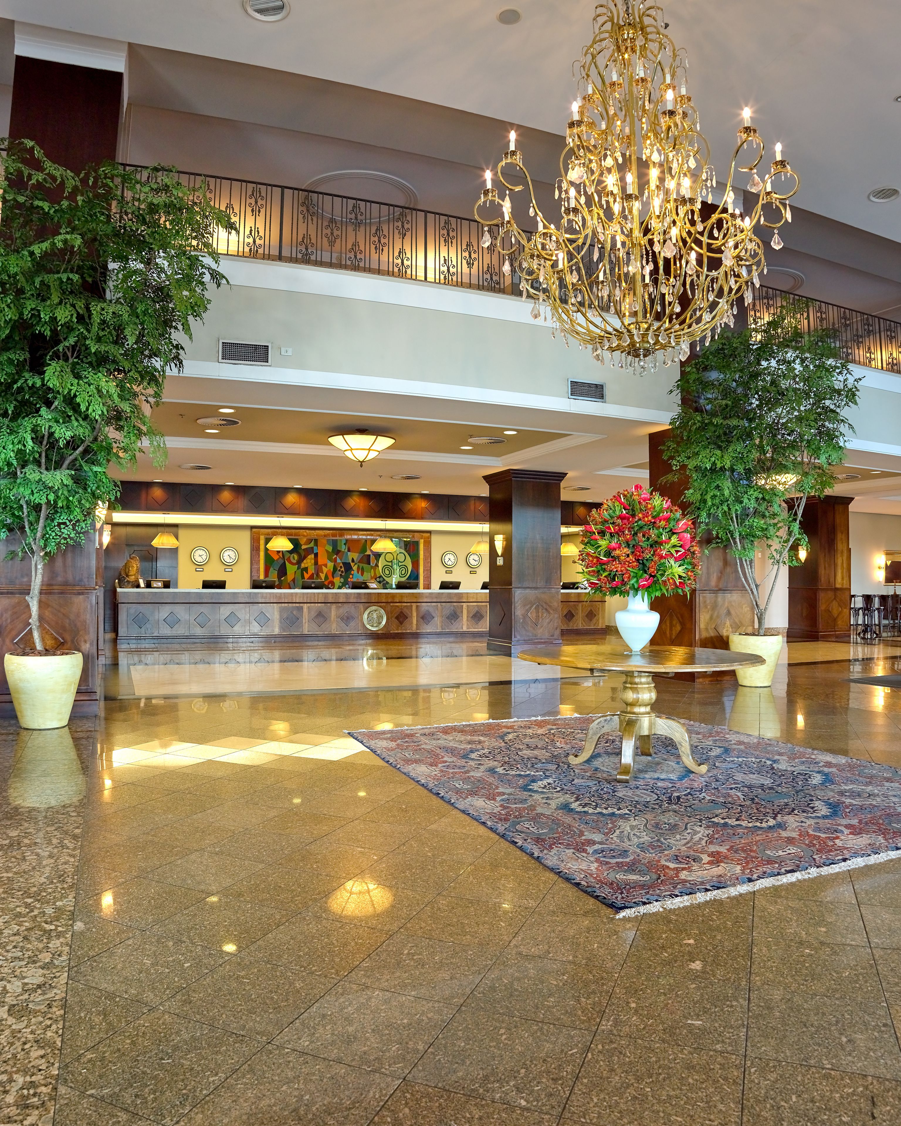 A spacious lobby with a grand chandelier, a reception desk, and a polished floor.