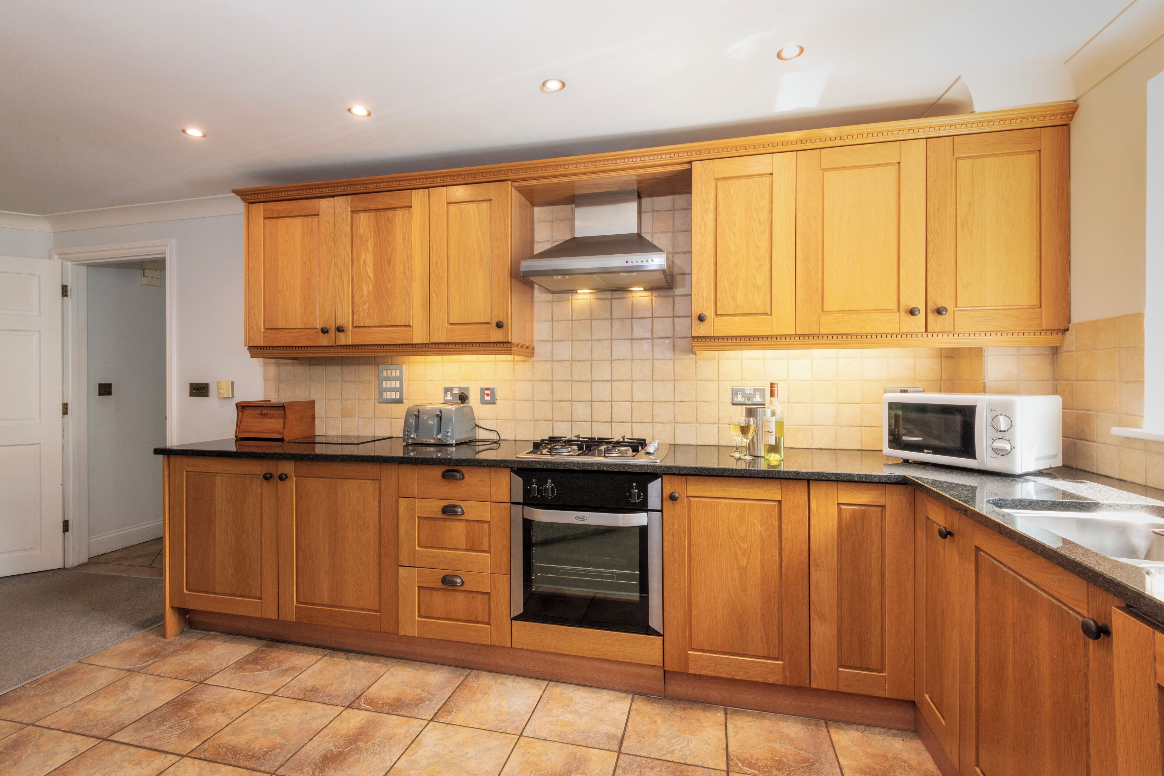 Cucina con mobili in legno, piano cottura a gas, forno, microonde e lavandino.