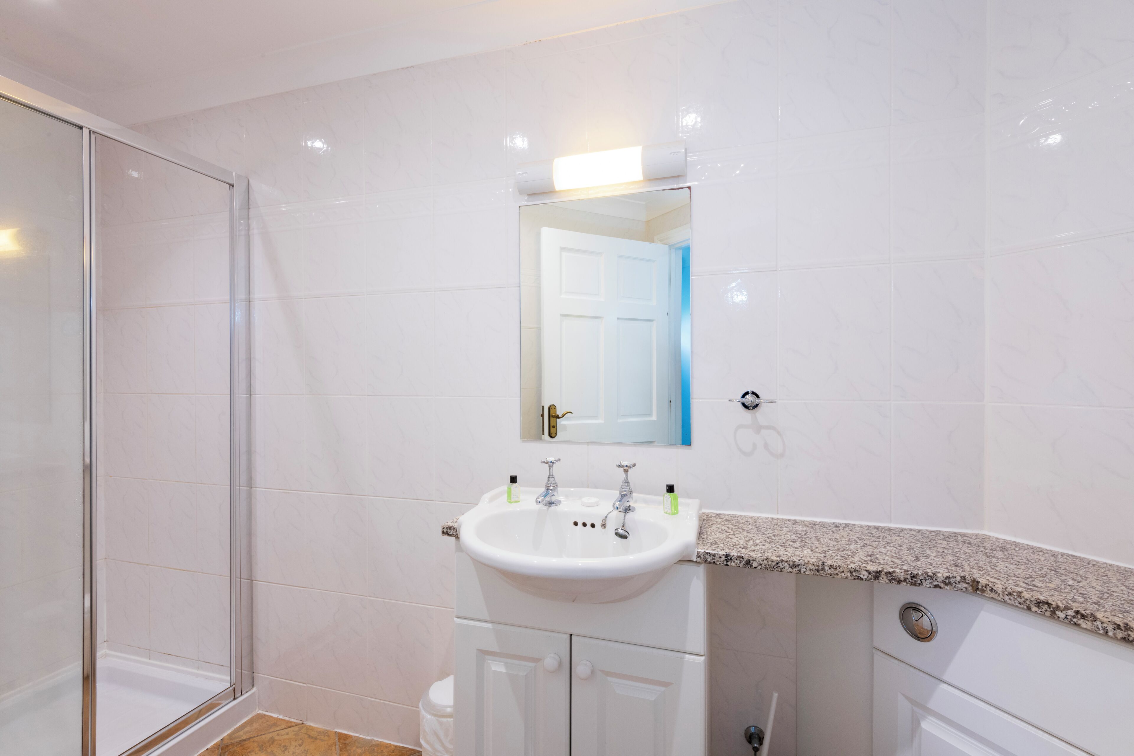 A bathroom with a white sink, a mirror, and a shower enclosure.