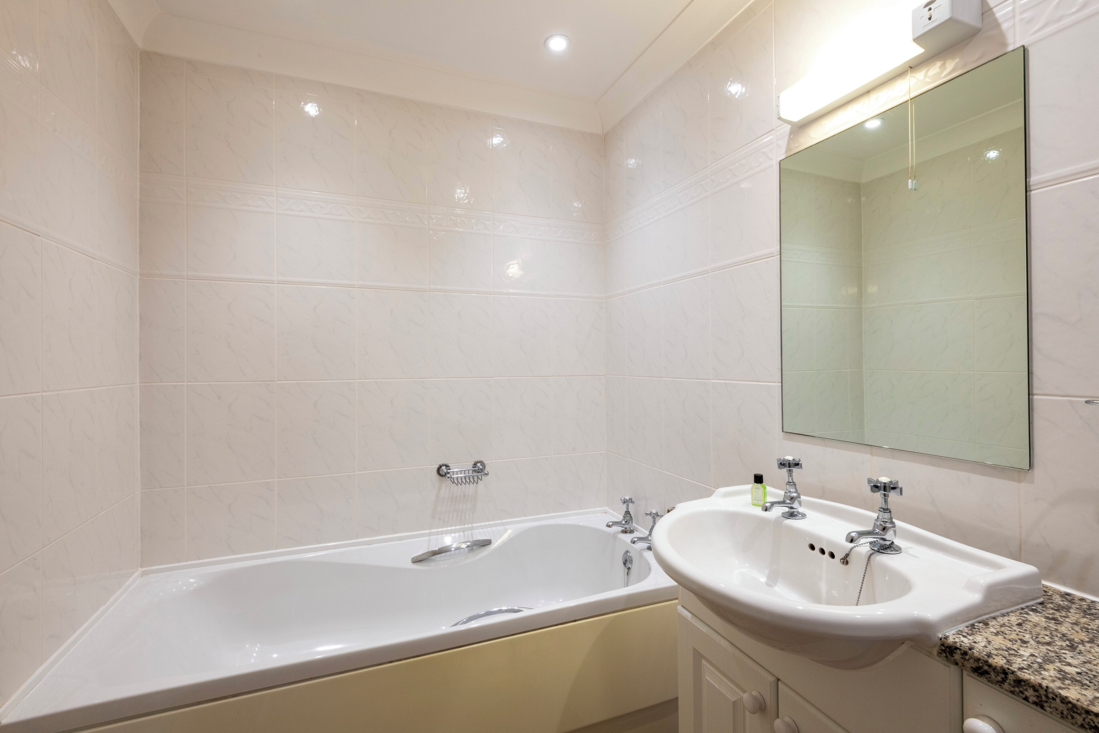 A modern bathroom with a large bathtub, a sink, and a mirror.