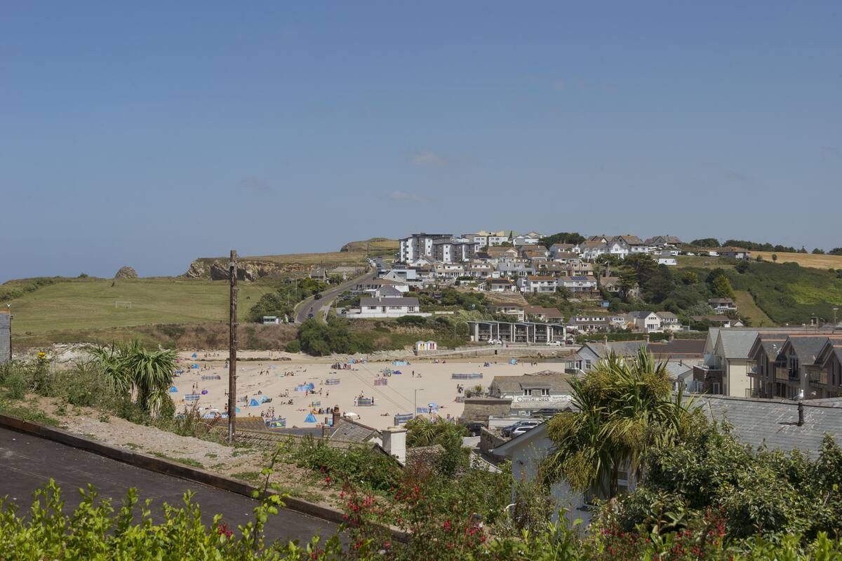 A coastal town with a beach, residential buildings, and a prominent hill.