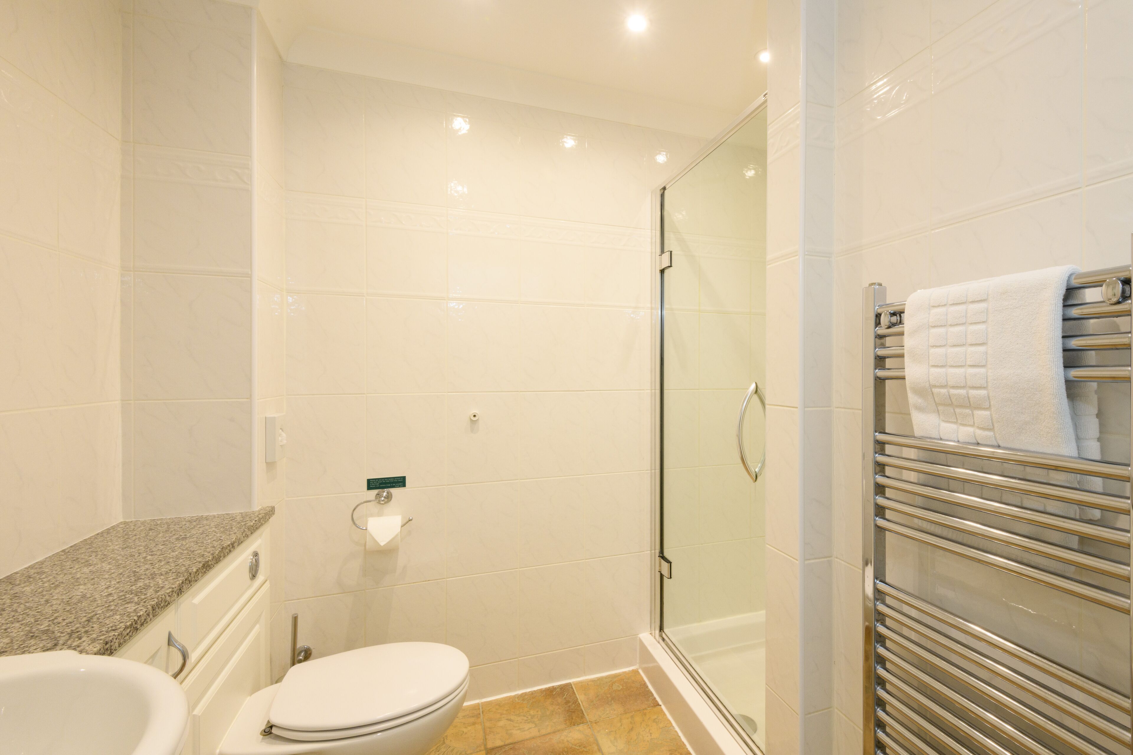 Une salle de bain avec une douche à parois de verre, des toilettes et un porte-serviettes avec des serviettes.