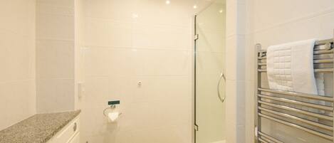 Une salle de bain avec une douche à parois de verre, des toilettes et un porte-serviettes avec des serviettes.