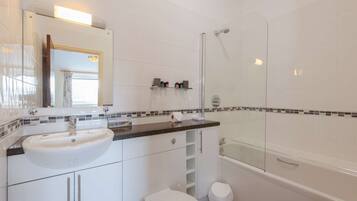 Een moderne badkamer met een witte wastafel, spiegel en een douchecabine van glas.