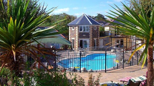 A swimming pool surrounded by a fence, with a stone building in the background. - Porth Veor Manor, Sure Hotel Collection by Best Western (Newquay)