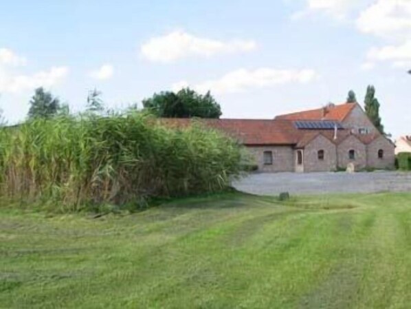 A rural building with a red-tiled roof, a small attached structure, and a paved driveway. - B&B Ter Gracht (Wevelgem)