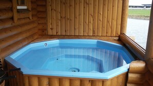 Un jacuzzi en una cabaña de madera con vista a un cuerpo de agua.