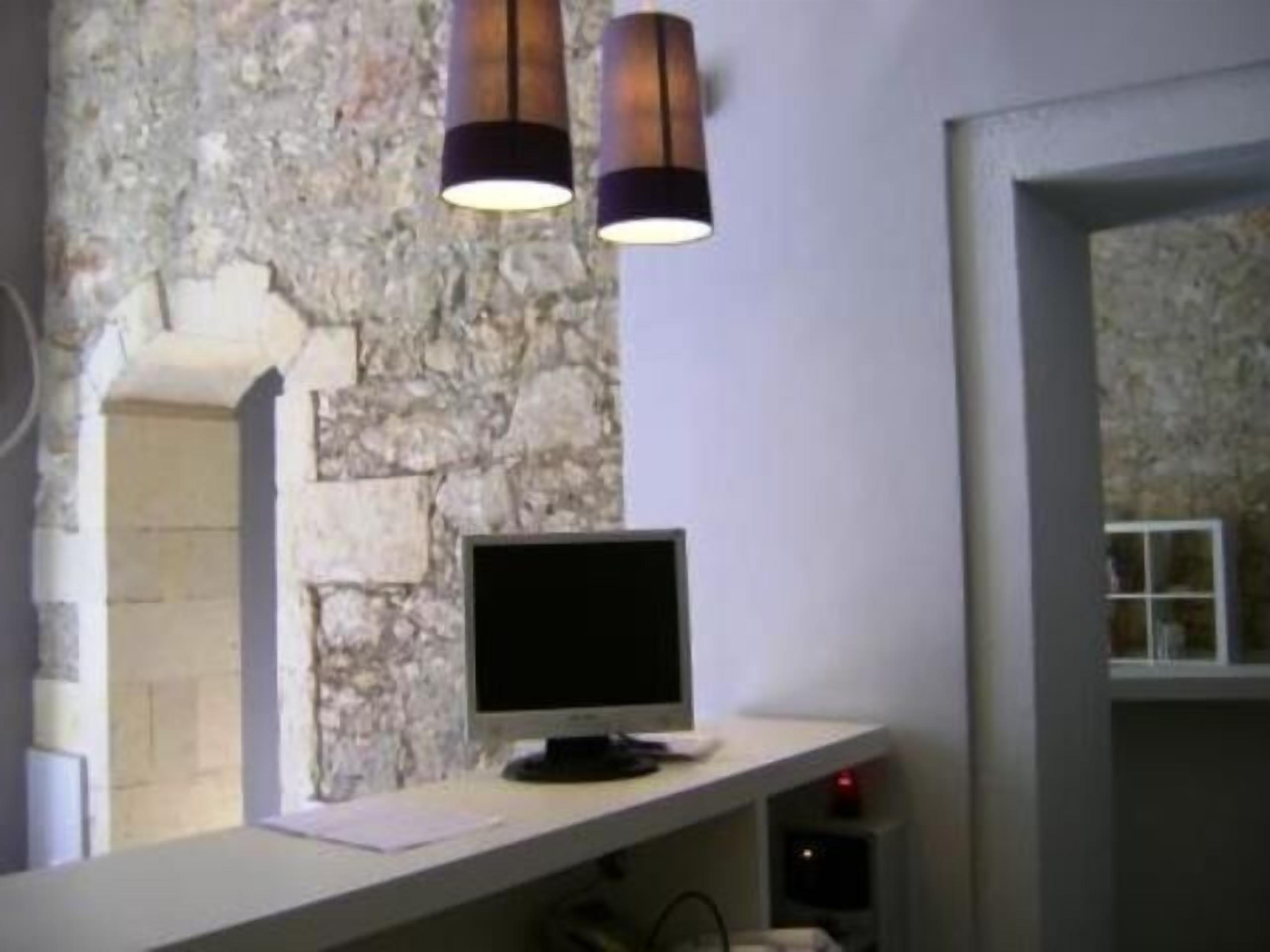 Ein Zimmer mit einer Steinswand, einem Flachbildfernseher auf einem weißen Regal und zwei hängenden Pendelleuchten.