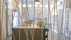 A modern kitchen with a marble backsplash, pendant lights, and a central island with a vase of flowers. - LoL Hostel Siracusa (Syracuse)