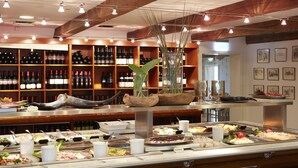 Uma área de buffet com diversas opções de comida e seleção de vinhos atrás do balcão.