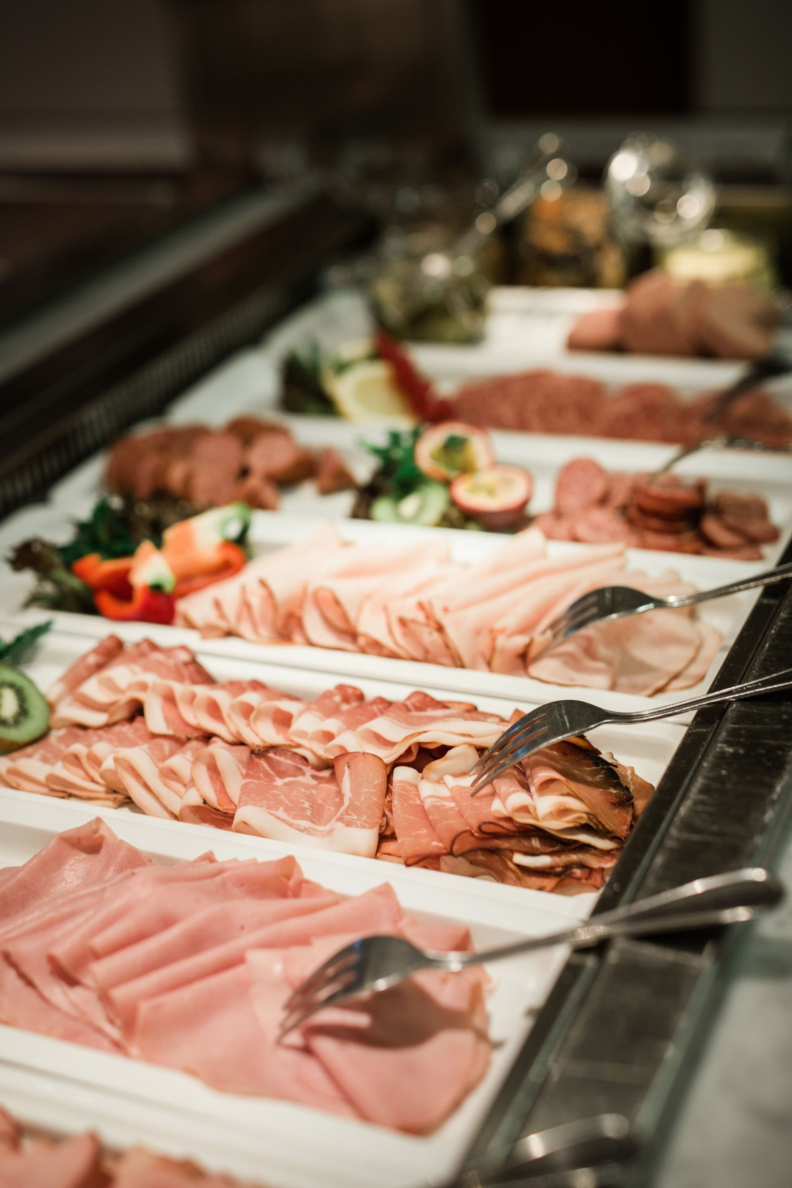 A buffet with various types of meat and garnishes.