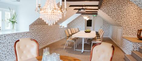 A dining area with a chandelier, a piano, and a staircase.