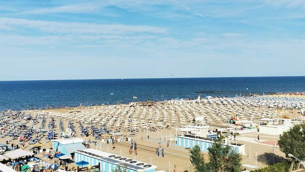 Une plage dotée de nombreuses chaises longues et de parasols, d’une tour de surveillance pour les sauveteurs, et offrant une vue dégagée sur la mer.