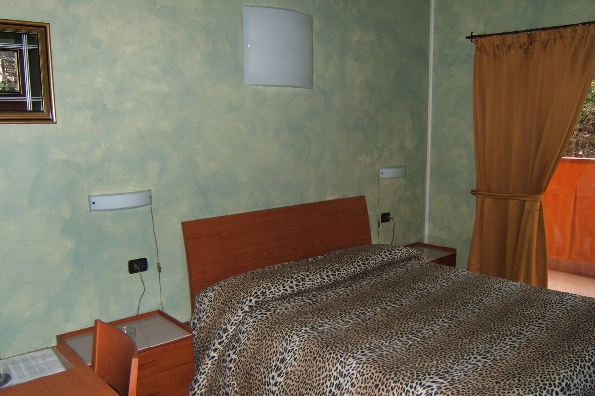 Un dormitorio con una cama de madera, una mesita de noche, una lámpara y un aplique de pared.