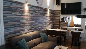 A modern living room with a sofa, coffee table, and a TV mounted on the wall. - Hotel Sfinx (De Panne)