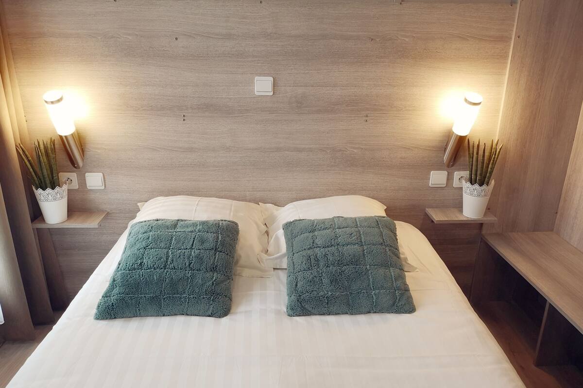 A double bed with two pillows, bedside tables with lamps, and a wooden headboard.