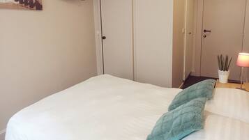 Un dormitorio con una cama, un televisor montado en la pared y una puerta con manija.