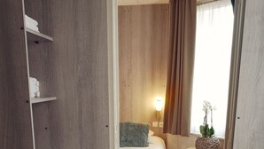 A hotel room with a bed, bedside table, lamp, and a view of the outdoors. - Hotel Sfinx (De Panne)