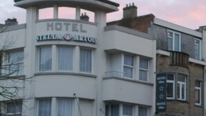A hotel building with multiple signs reading "Hotel SFINX" and "Hotel Stella Artis". - Hotel Sfinx (De Panne)