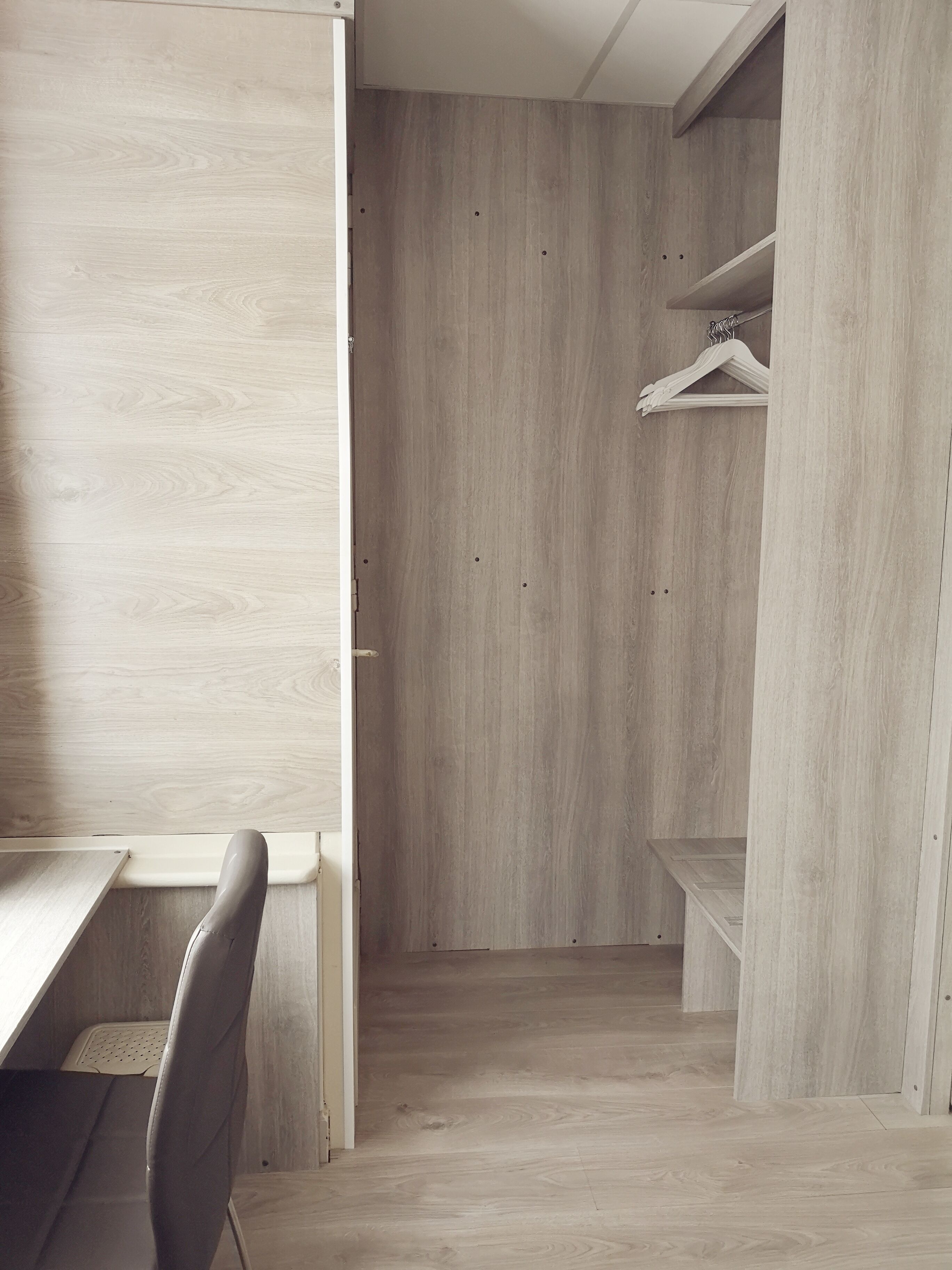 Un dressing moderne et minimaliste avec des panneaux en bois, une chaise et une petite table.