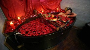 A bathtub filled with rose petals and candles, suggesting a romantic setting. - Hotel Garten (Slavonski Brod)