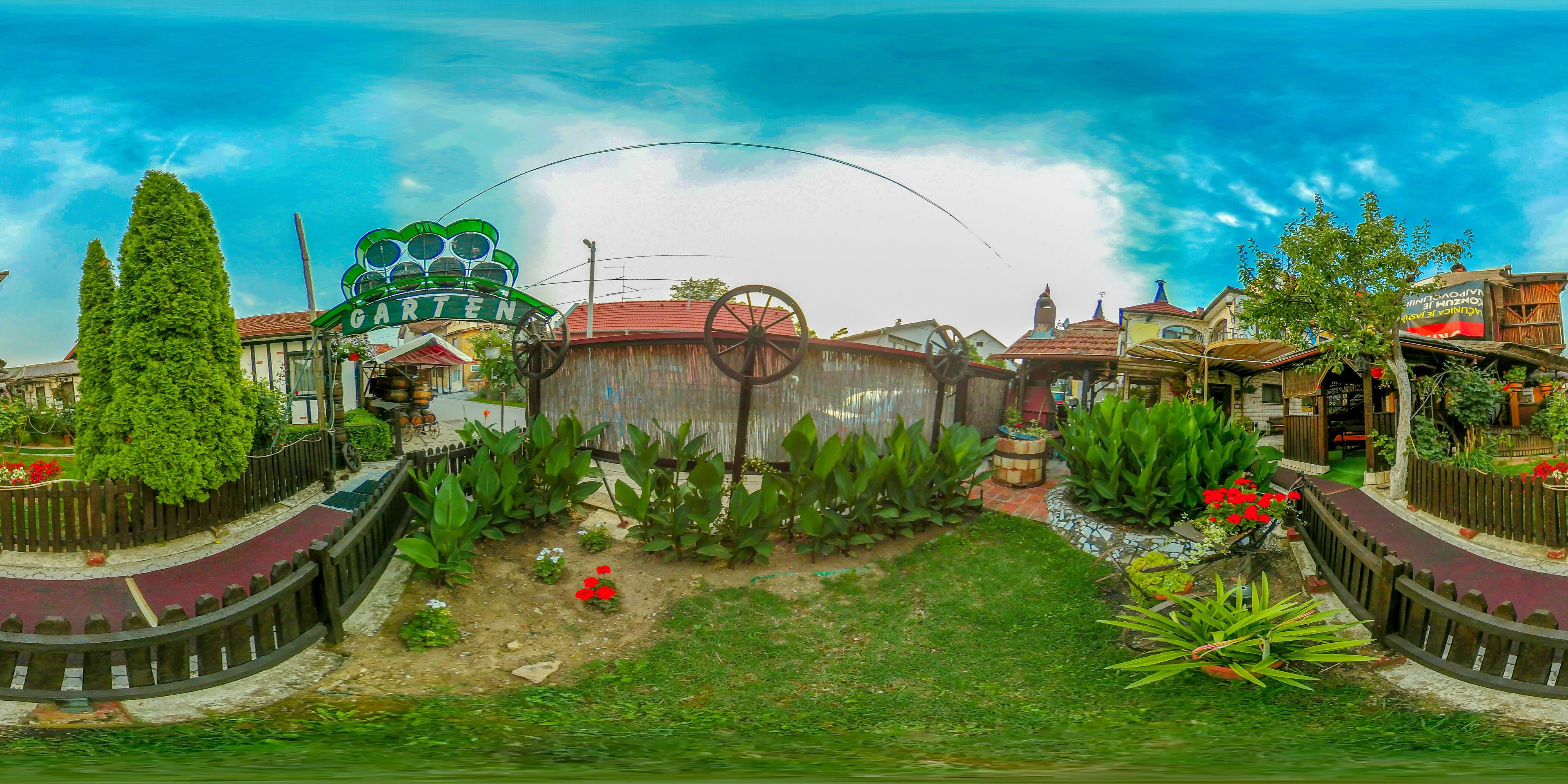A garden area with a fountain, a wooden fence, and a variety of plants.