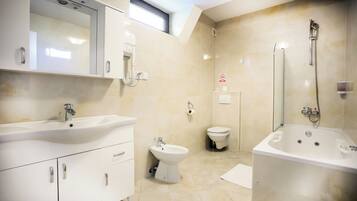 Un baño moderno con lavamanos grande, bidé, inodoro y bañera.