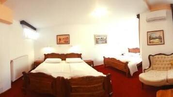 A hotel room with a large bed, a sofa, a TV, and a desk.