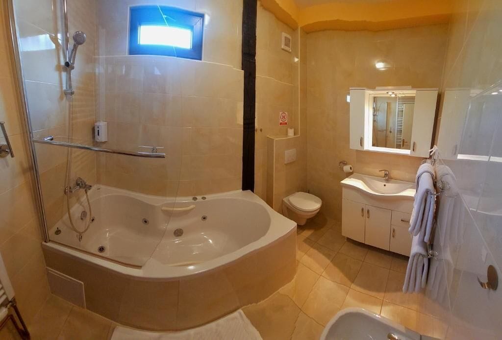 Un baño moderno con una bañera independiente grande, una zona de ducha separada, un inodoro y un lavamanos con un espejo encima.