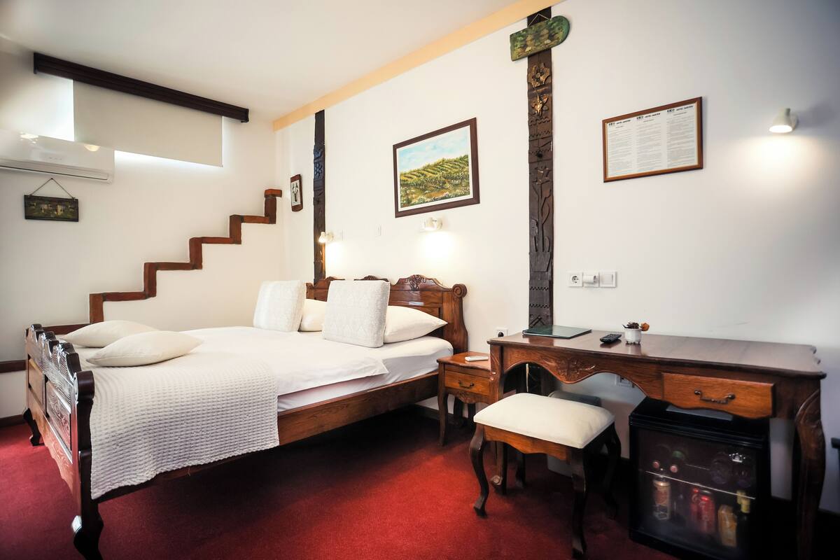 A bedroom with a wooden bed, a desk, a chair, and a small cabinet.