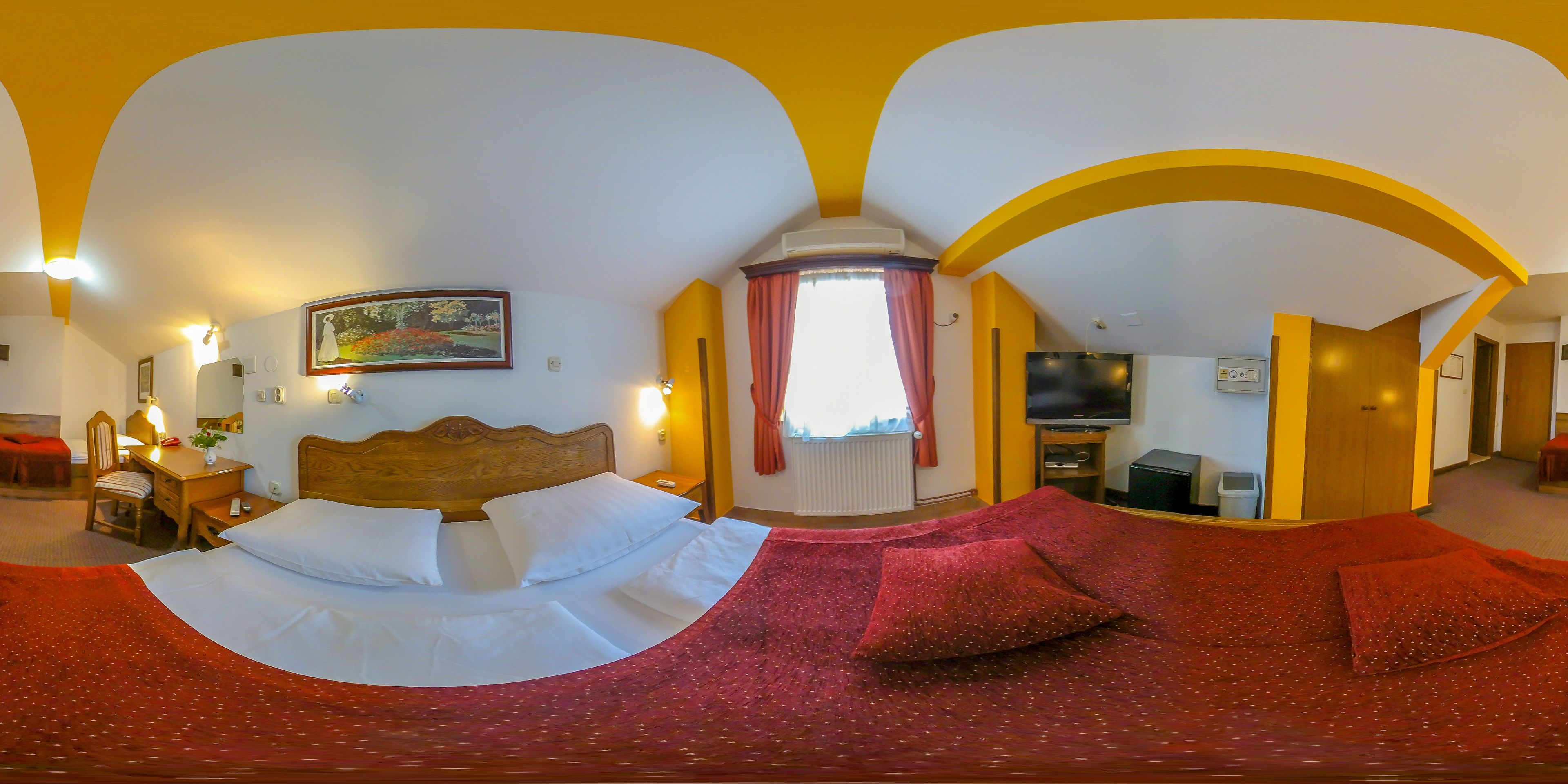 A hotel room with a bed, a desk, a chair, a TV, and a window with curtains.